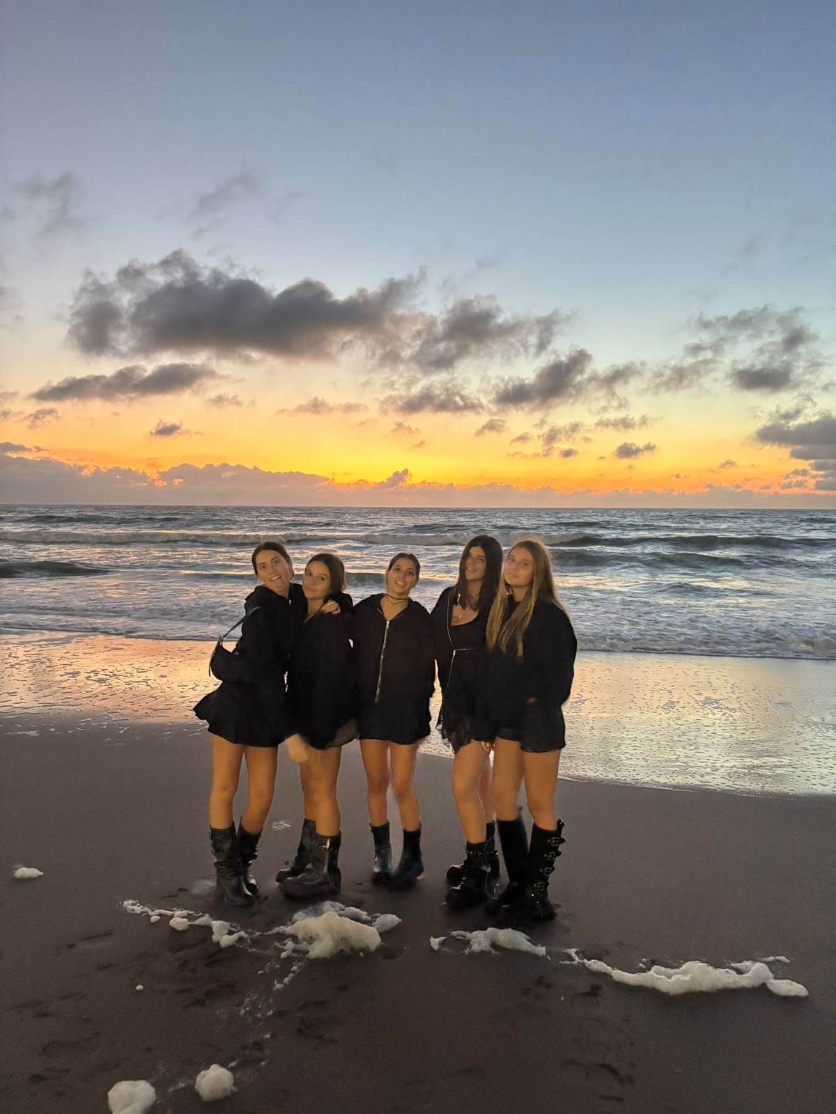 Amigas posando juntas en la playa de Pinamar con atardecer de fondo